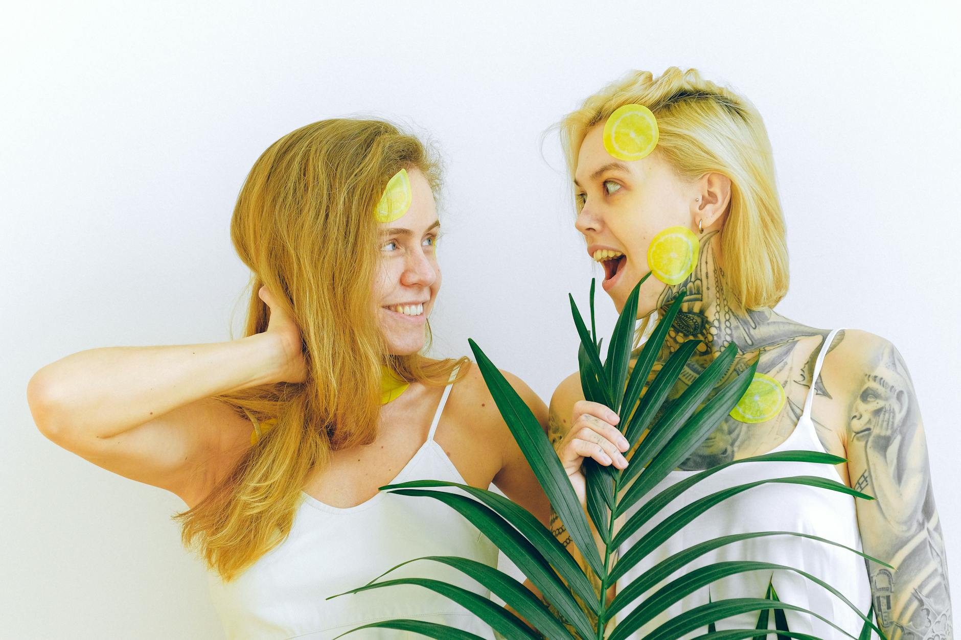 Two women laughing together with citrus and greenery, expressing joy and connection