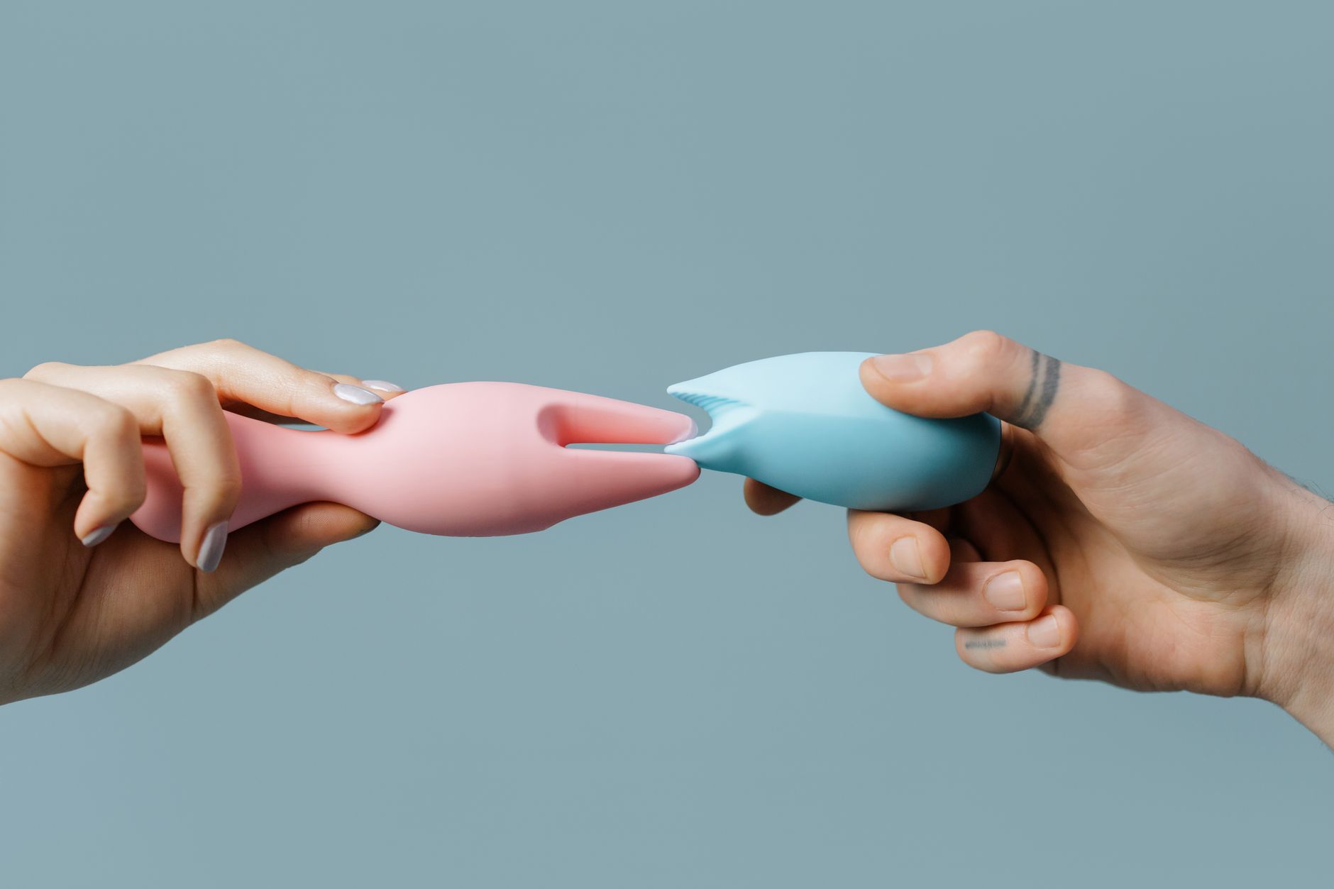 A hand holding an orange vibrator against a minimalistic purple backdrop