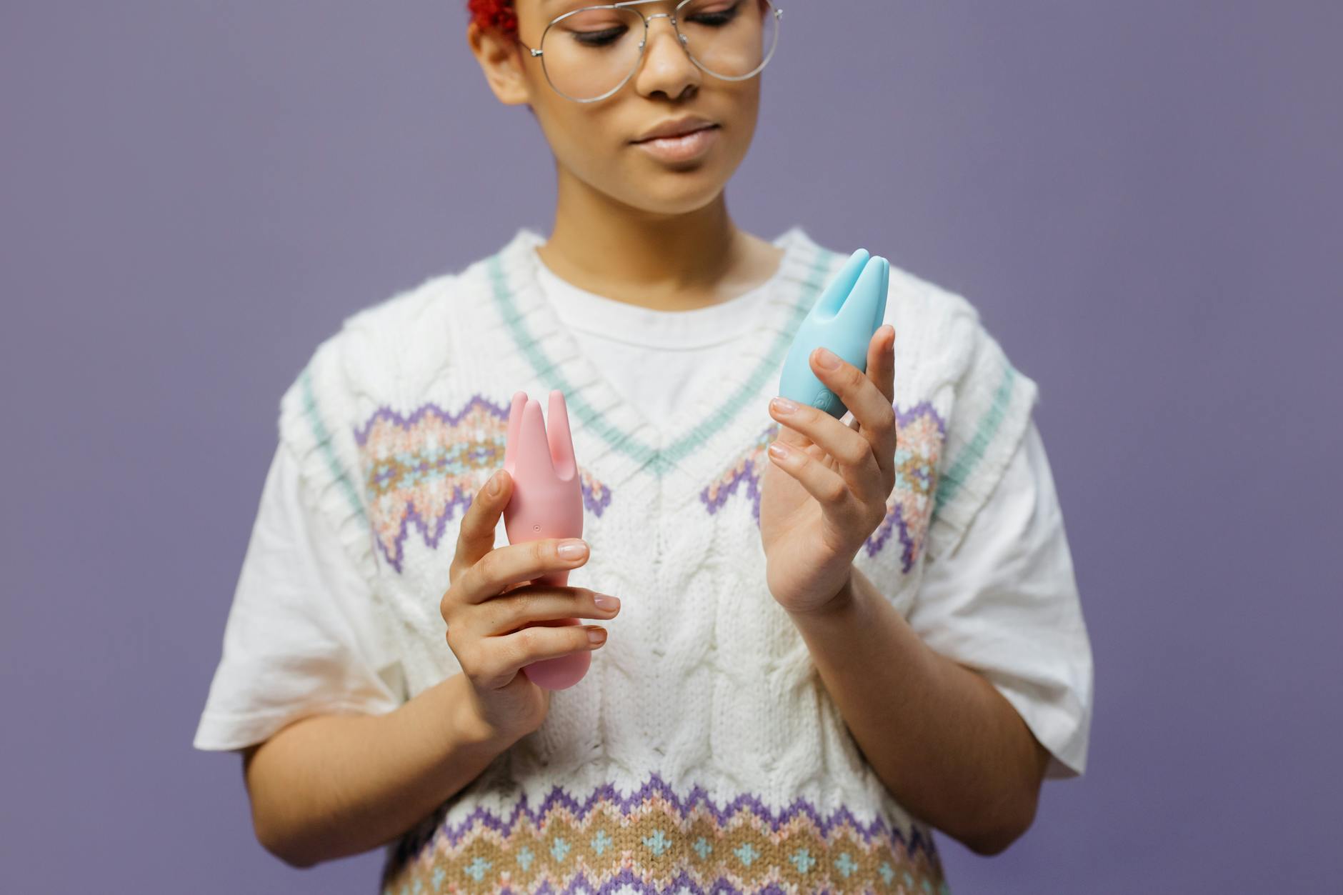 Close-up of hands holding a blue personal massager against a knitted sweater